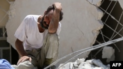 FILE - A man looks on as Syrian civil defense workers look for survivors under the rubble of a collapsed building following reported airstrikes in the rebel-controlled neighborhood of Karm Homad in Aleppo, July 17, 2016.