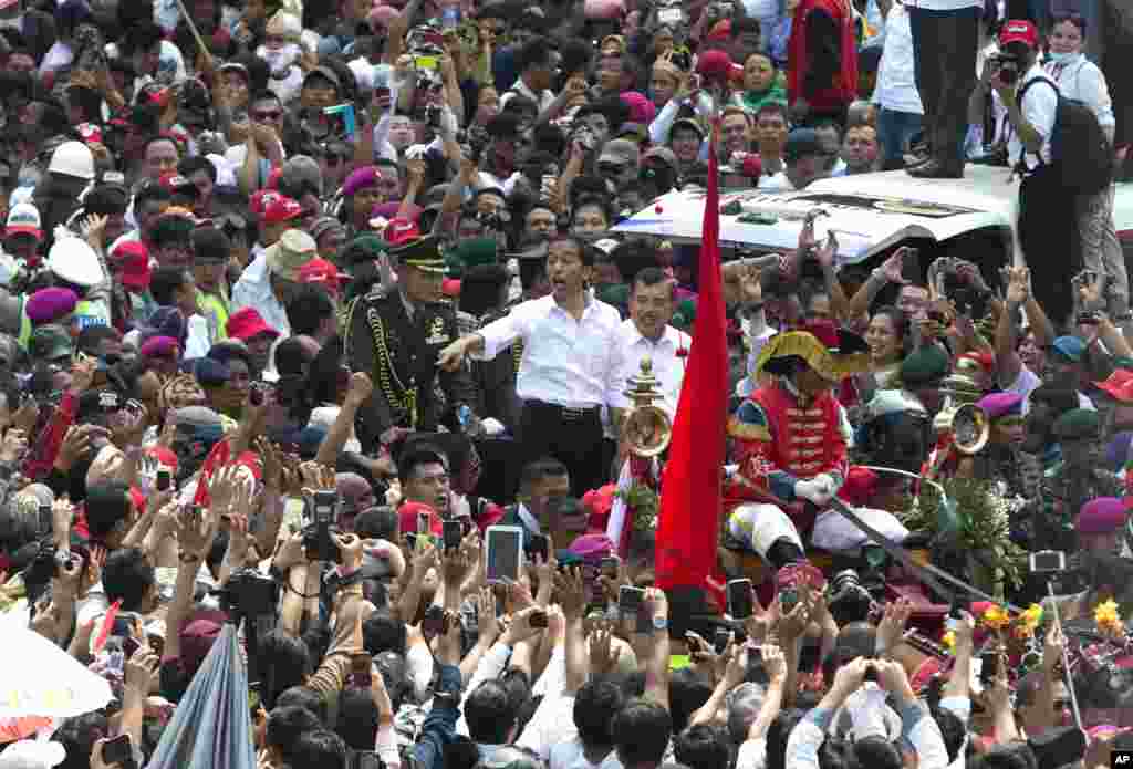 Tổng thống Indonesia Joko Widodo ra dấu trước đám đông trong một cuộc diễu hành đường phố sau lễ nhậm chức tại Jakarta. 