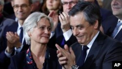 Conservative presidential candidate Francois Fillon applauds while his wife, Penelope, looks on as they attend a campaign meeting in Paris, Jan. 29, 2017. Financial prosecutors are investigating whether the former prime minister's wife was paid for work she didn't do. 