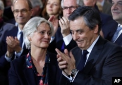 FILE - Conservative presidential candidate Francois Fillon applauds while his wife, Penelope, looks on as they attend a campaign meeting in Paris, Jan. 29, 2017.