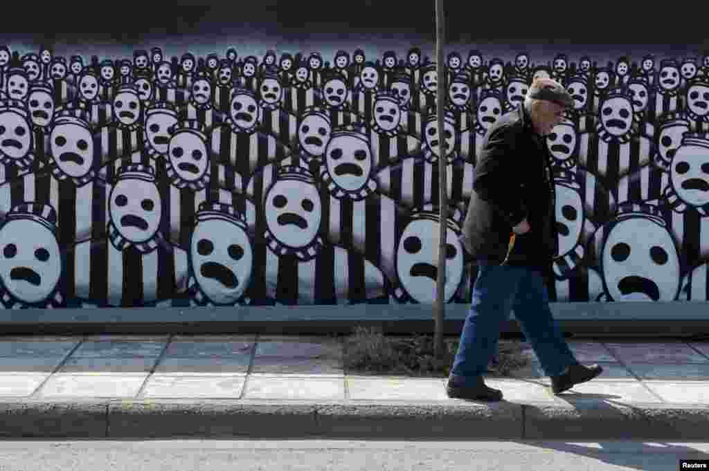 Seorang pria berjalan melewati graffiti yang didedikasikan untuk Holocaust di bagian utara kota pelabuhan Thessaloniki.
