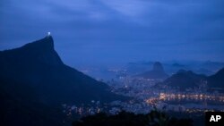 FILE - The Christ the Redeemer statue stands atop the Corcovado Mountain, left, at dawn in Rio de Janeiro, Brazil, July 29, 2016. 