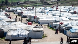 FILE - Women and children walk at Roj camp, where relatives of people suspected of belonging to the Islamic State group are held, in the countryside near al-Malikiyah in Syria's northeastern Hasakah province, on March 28, 2021.