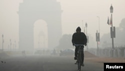 A man rides his bicycle in front of the India Gate shrouded in smog in New Delhi, Dec. 26, 2018.