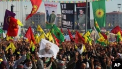 FILE - Masked people in guerrilla outfits hold up a poster of of jailed Kurdish rebel leader Abdullah Ocalan as they demonstrate during the Nowruz celebrations in southeastern Turkish city of Diyarbakir, Turkey, March 21, 2014. 