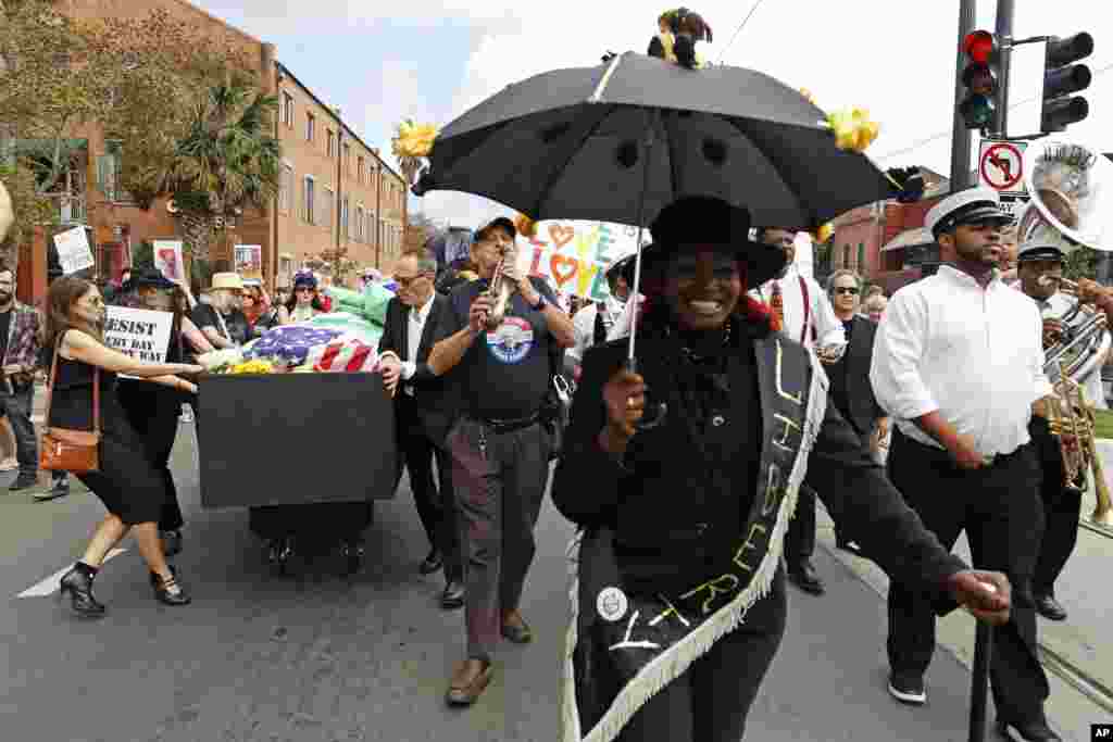 Members of the Mahogany Brass Band lead a mock second line jazz funeral procession in front of The Statue of Liberty in a coffin down the streets of New Orleans in protest of the inauguration of Donald Trump Friday, Jan. 20, 2017.