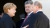 German Chancellor Angela Merkel, left, Russian President Vladimir Putin, right, and Ukrainian president-elect Petro Poroshenko, center, talk after a group photo in NOrmandy, France, June 6, 2014.