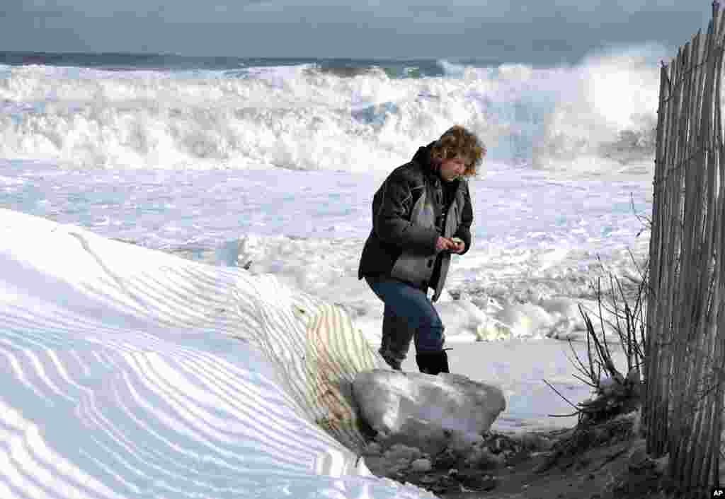 Cindy Roche moves away after taking pictures of rough surf at Salisbury Beach, Jan. 3, 2014, in Salisbury, Massachusetts, in the wake of a winter storm which dumped up two feet of snow in some areas north of Boston. 