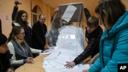 Les membres de la commission électorale locale ouvrent une urne pour le dépouillement lors de l'élection présidentielle à Saint-Pétersbourg, en Russie, le 18 mars 2018.