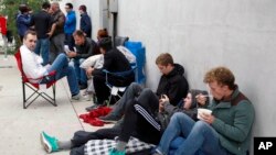 FILE - People wait in line after spending the night for the new Apple watch at Maxfield, a high-end fashion boutique in Los Angeles, April 24, 2015.