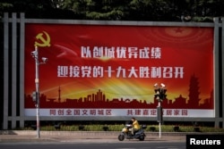 A man rides an electric scooter past a poster, promoting the 19th National Congress of the Communist Party of China