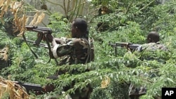 Somali government soldiers in the bush take position during clashes between insurgents and Somali government soldiers with AU peacekeeping forces in southern Mogadishu's Bakara market neighborhood, May 22, 2011.