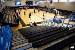 Yeshiva University players, foreground, warm up in a mostly empty Goldfarb Gymnasium at Johns Hopkins University.