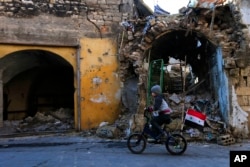 FILE - Syrian boy rides his bike past the destruction in the once rebel-held Jalloum neighborhood of eastern Aleppo, Syria.