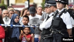 A young boy plays with a water pistol as onlookers stand at the police cordon as police search a property in Barking Road, east London, June 4, 2017.