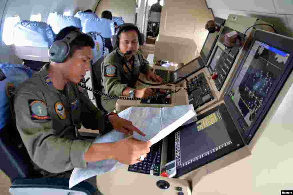 Two members of the Indonesian Navy&#39;s Tactical Commanding Operator (TACCO) help with the search for AirAsia flight QZ 8501 on board a CN235 aircraft over Karimun Java, in the Java Sea, Dec. 28, 2014. (Antara Foto)