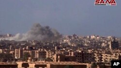 De la fumée et des débris après le bombardement de la ville de Deir el-Zour par le gouvernement syrien lors d'une bataille contre les militants de l'Etat islamique en Syrie, d'image d'une vidéo publiée le 2 novembre 2017 par l'agence de presse officielle syrienne SANA.