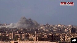 Esta imagen tomada de un video divulgado el 2 de noviembre de 2017 por la agencia oficial de noticias siria SANA, muestra humo tras el bombardeo del Ejército sirio contra militantes de ISIS en Deir el-Zour, Siria.