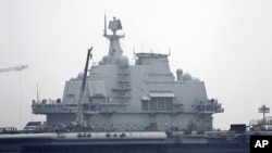 Workers are seen on the flight deck of the China's first aircraft carrier, former 'Varyag' of Ukraine, which is under restoration at a shipyard in Dalian in northeastern China's Liaoning province, July 27, 2011