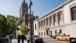 Para pejalan kaki melintas di depan sudut jalan pada pintu masuk Central Park New York. Para aktivis menggalang dana untuk pembuatan patung-patung tokoh perempuan yang mengubah sejarah, di lokasi itu, 6 Oktober 2016. (Foto: AP/arsip)