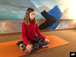 In this May 14, 2019 photo, Aeva Schifferli, 12, demonstrates a stress-relieving breathing exercise at her mother's yoga studio in East Aurora, N.Y.