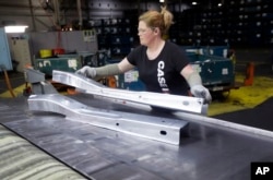 FILE - United Auto Workers line worker Crystal McIntyre unloads parts from a stamping machine at the General Motors Pontiac Metal Center in Pontiac, Mich., April 30, 2015.