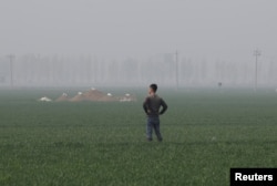 A man stands next to tombs in the field on the outskirts of Rongcheng county, one part of the new special economic zone Xiongan New Area, China, April 6, 2017.