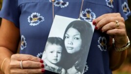 Leigh Boughton Small, an adoptee from Vietnam, poses with a photo of her and her mother as a child and her birth mother, at her home in the US state of Maine on October 29, 2019.
