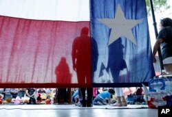 FILE - U.S. Rep. Joaquin Castro, D-Texas (C) is seen through a Texas flag as he waits to speak during a Rally For Our Children event to protest a new "zero-tolerance" immigration policy that has led to the separation of families, May 31, 2018, in San Antonio, Texas.