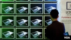 FILE - A visitor looks at ASUS computer screens at the Computex trade show in Taipei.