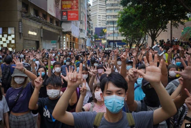 FILE - Protesters against the new national security law gesture with five fingers, signifying the "Five demands - not one less" on the anniversary of Hong Kong's handover to China from Britain in Hong Kong, Wednesday, July. 1, 2020. (AP Photo/Vincent Yu)