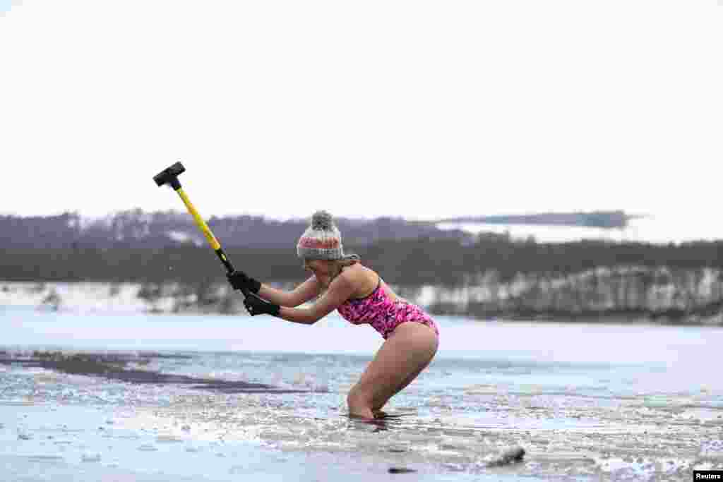 Nicky Goode uses sledgehammer to break the ice at Loch Insh, Scotland, Britain.