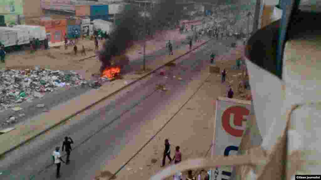 Quelques personnes marchent à pied à côté d'objets en flammes sur les rues de Luanda,, 5 octobre 2015. Photo de Kolly Antonio Mwanza.
