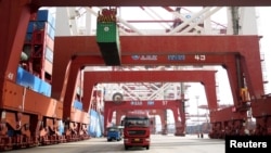 Beberapa truk membawa kontainer di pelabuhan di Qingdao, Provinsi Shandong, China, 8 April 2018. 