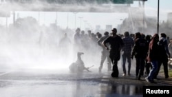 Protestors are sprayed with water by Argentine police as they block a road during a 24-hour national strike in Buenos Aires, Argentina, April 6, 2017.