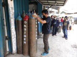 Seorang pegawai toko pengisian ulang tabung oksigen di Manggarai, Jakarta Selatan, mengecek tabung oksigen untuk keperluan medis, Senin, 5 Juli 2021. (Foto: Indra Yoga/VOA)