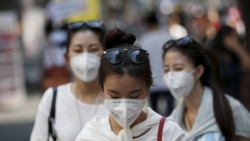A tourist wearing a mask to prevent contracting Middle East Respiratory Syndrome (MERS) uses her mobile phone at Myeongdong shopping district in central Seoul, South Korea, June 10, 2015.