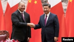 FILE - King Tupou VI, left, of Tonga shakes hands with Chinese President Xi Jinping at The Great Hall of the People, in Beijing, March 1, 2018.