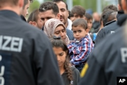 FILE - German policemen register refugees at the rail station in Freilassing, Germany, Sept. 14, 2015.