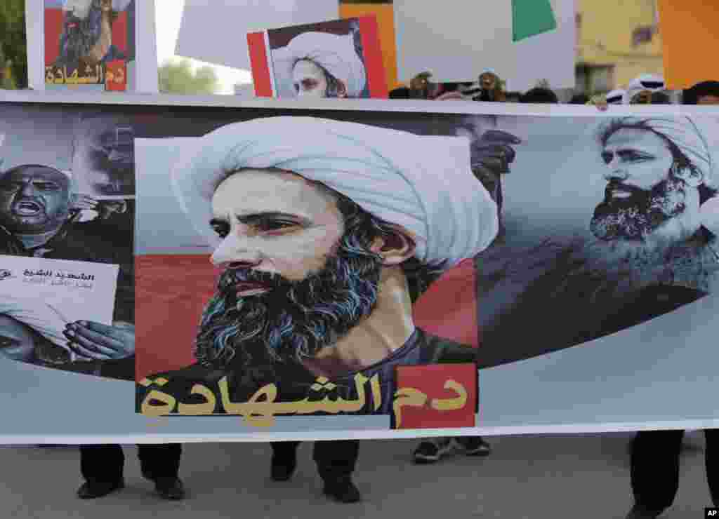 Para demonstran Bahrain membawa banner bergambarkan ulama Syiah Saudi Sheikh Nimr al-Nimr dan bertuliskan, &quot;darah martir,&quot; saat sebuah unjukrasa di Sitra, Bahrain. Polisi melepaskan gas air mata kepada para demonstran yang melemparkan batu dan bom molotov saat bentrokan pecah di pawai protes menentang eksekusi al-Nimr yang dilakukan oleh Saudi.