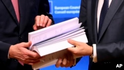 EU chief Brexit negotiator Michel Barnier, left, and European Council President Donald Tusk flip through the pages of a draft withdrawal agreement at the Europa building in Brussels, Nov. 15, 2018.