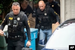 Oficiales de policía llevan bolsas de evidencia desde la casa de la familia del sospechoso en el tiroteo del Festival del Ajo de Gilroy, Santino William Legan, el lunes 29 de julio de 2019 en Gilroy, California.