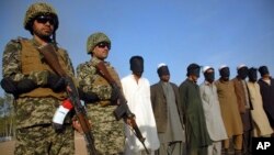 Pakistani paramilitary soldier stand guard next to suspects arrested during a search operation in Shah Kass, an area of Pakistani Khyber tribal region along Afghan border, March 3, 2017. 