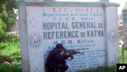 FILE - Police shelter behind a hospital sign as they guard a hospital in Butembo, Congo, April 20, 2019, after militia members attacked an Ebola treatment center in the city’s Katwa district overnight.