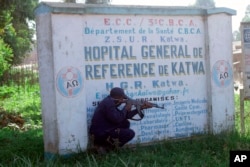 FILE - Police shelter behind a hospital sign as they guard a hospital in Butembo, Congo, April 20, 2019, after militia members attacked an Ebola treatment center in the city’s Katwa district overnight.