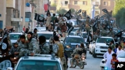 FILE - Fighters from the Islamic State group parade in Raqqa, north Syria, June 30, 2014. Former British spy chief says militants more than doubled the recruitment of foreign fighters to as much as 31,000 over the past 18 months.