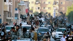 FILE - Islamic State fighters parade in Raqqa, Syria, June 30, 2014. A former British spy chief said militants at that point had more than doubled the recruitment of foreign fighters, to as much as 31,000, over the previous 18 months.