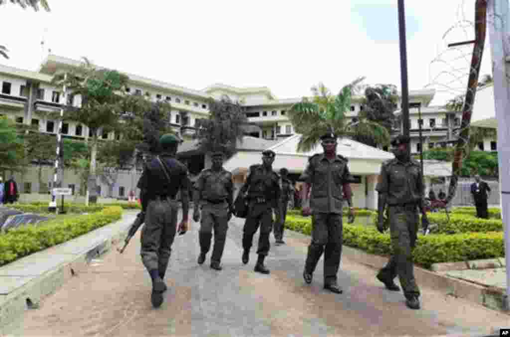 Nigerian soldiers walk outside United Nations headquarters a day after a suicide bomber crashed through an exit gate and detonated a car full of explosives in the building's reception area, in Abuja, Nigeria Saturday, Aug. 27, 2011.