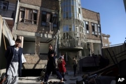 FILE - Afghans gather in front of the Shiite cultural center after a suicide attack in Kabul, Afghanistan, Dec. 28, 2017.