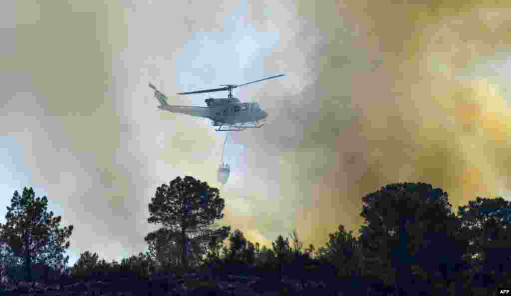 A helicopter drops water over a wildfire in Pinet, in the eastern Spanish region of Valencia.